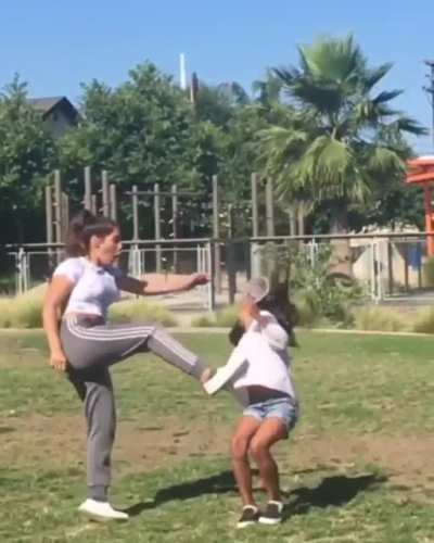 Attempting to kick a cup off her friends head
