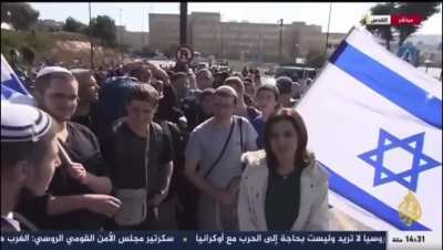 Crowd of Israeli colonists heard Aljazeera reporter speaking Arabic to the camera so they attempted to disrupt the live report by blocking the camera and shouting things like "Allah," and "Mohammad"