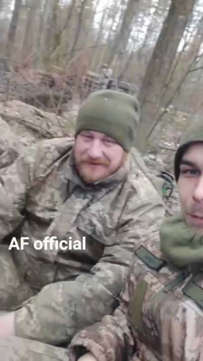 Band of brothers: A Ukrainian squad warm themselves around the campfire.
