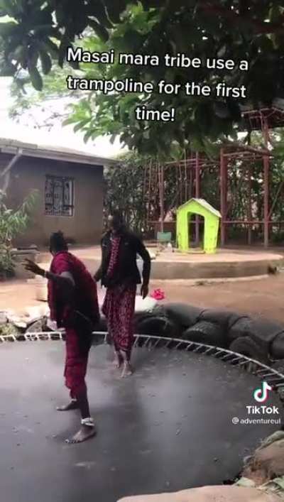 Two members of the Masai Mara in Kenya experiencing a tramploline for the first time are overcome with joy.